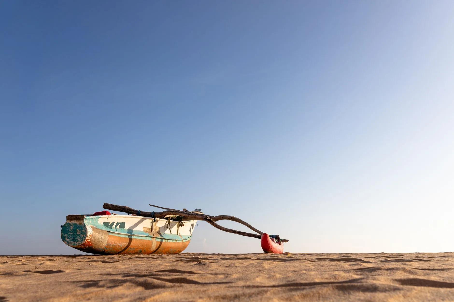 Plage de la côte est du Sri Lanka avec un bateau de pêche traditionnel dans les eaux turquoise de Trincomalee