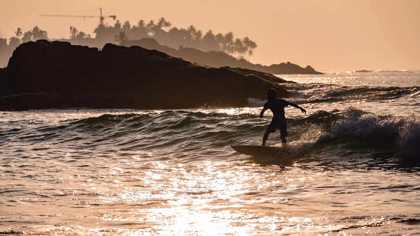 Surfeur en silhouette sur les vagues de Mirissa au coucher du soleil, Sri Lanka